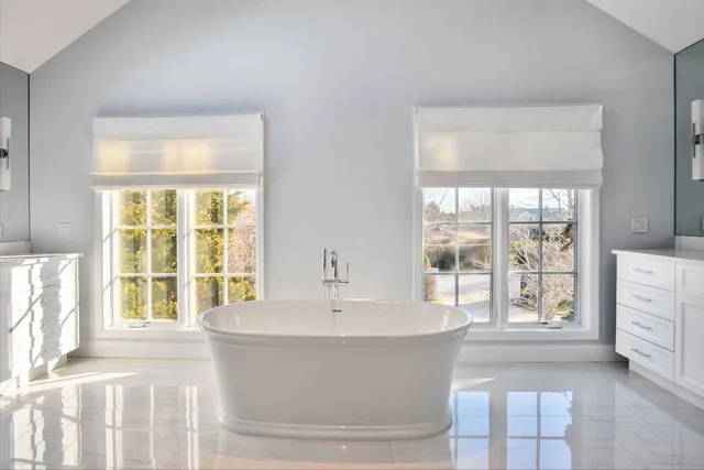 a white bath tub sitting in a spacious bedroom next to a window