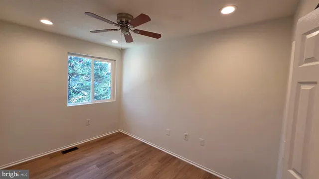 an empty room with a window and a fan