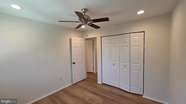 an empty room with wooden floor closet and windows