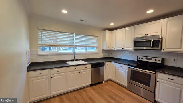 a kitchen with stainless steel appliances granite countertop white cabinets granite counter tops and a window
