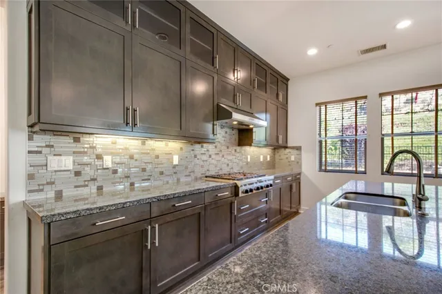 a kitchen with stainless steel appliances granite countertop a stove a sink and a microwave
