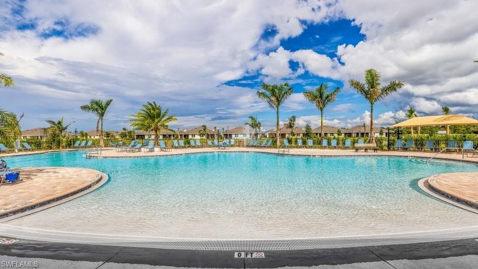 17971 Shade Tree Loop Babcock Ranch, FL 33982 - Photo 20 of 26 Expansive community swimming pool with a shallow entry area, surrounded by palm trees and lounge chairs