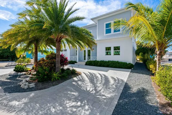 a view of a house with a yard and palm trees