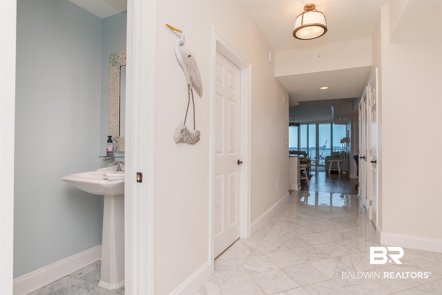 27800 Canal Road, Unit 411 Orange Beach, AL 36561 - Photo 32 of 49 Light-toned walls with contrasting baseboards, a white paneled door, and a flush mount ceiling light illuminate the polished tile flooring