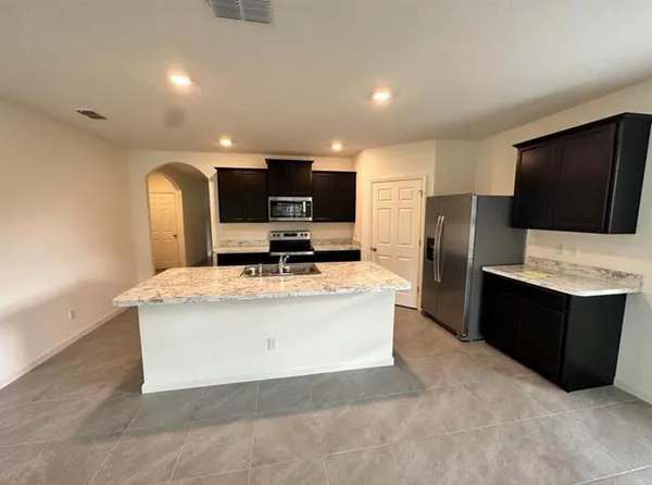 a view of kitchen with kitchen island stainless steel appliances a sink cabinets and refrigerator