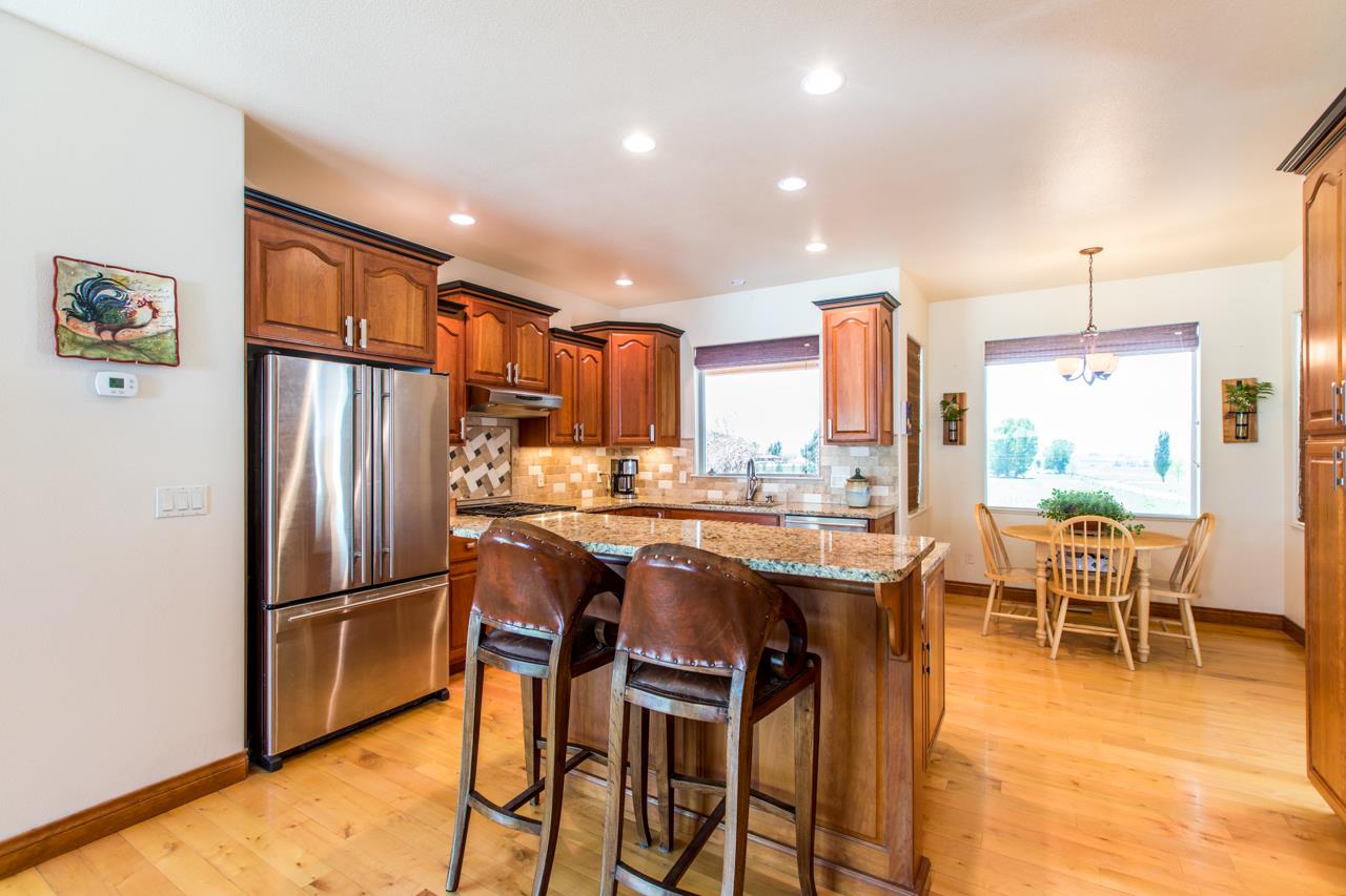 2174 M Road Grand Junction, CO 81505 - Photo 6 of 42 a kitchen with stainless steel appliances granite countertop a refrigerator a stove a sink a dining table and chairs with wooden floor