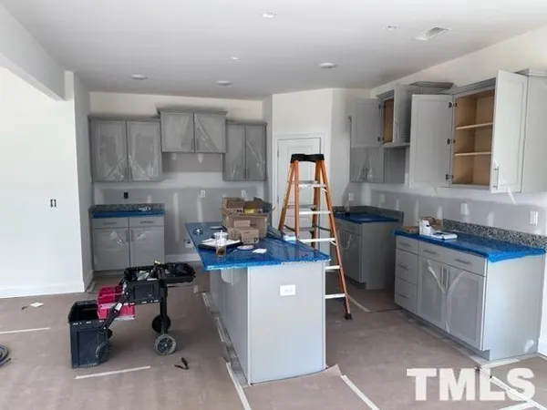 a kitchen with kitchen island a stove a sink dishwasher and white cabinets with wooden floor