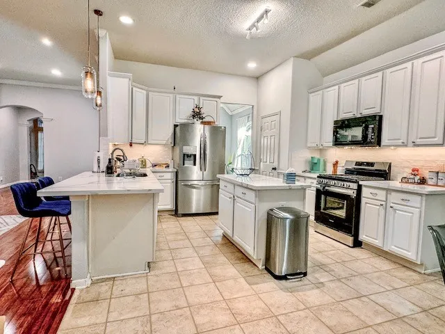 a kitchen with kitchen island granite countertop appliances cabinets and a sink