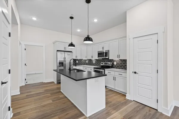 a kitchen with stainless steel appliances granite countertop a sink a stove and a refrigerator