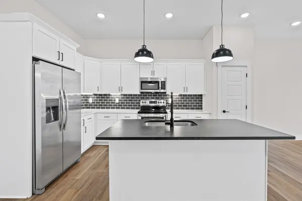 a kitchen with stainless steel appliances granite countertop a sink a stove and a wooden floors