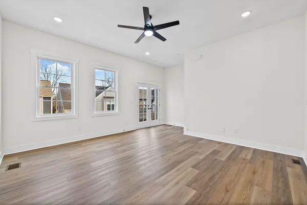a view of empty room with wooden floor and ceiling fan