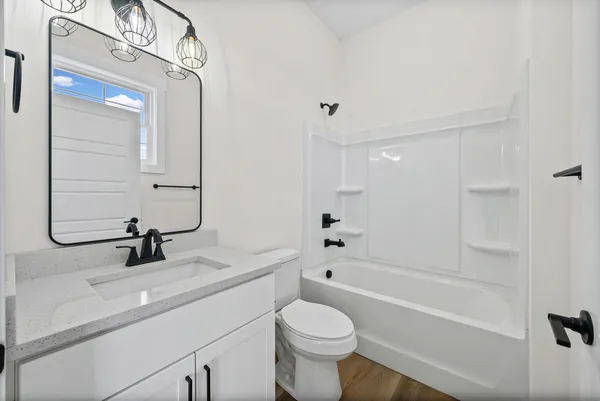 a view of a hallway with wooden floor and a bathroom