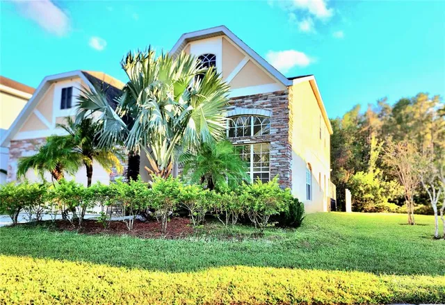 a view of a house with a big yard and large trees