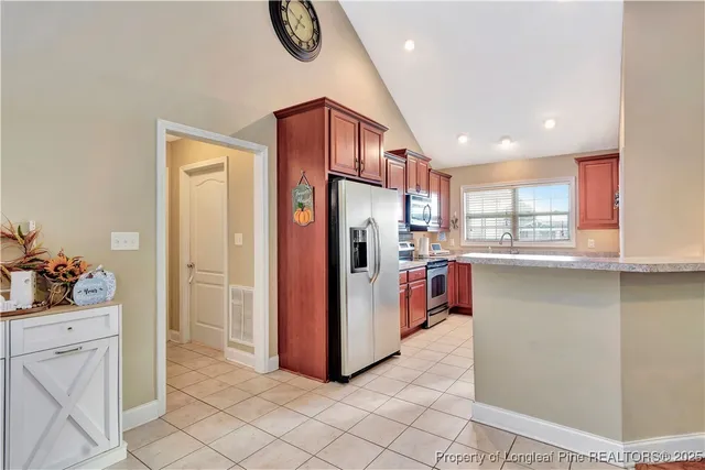 a kitchen with stainless steel appliances kitchen island granite countertop a refrigerator and a sink