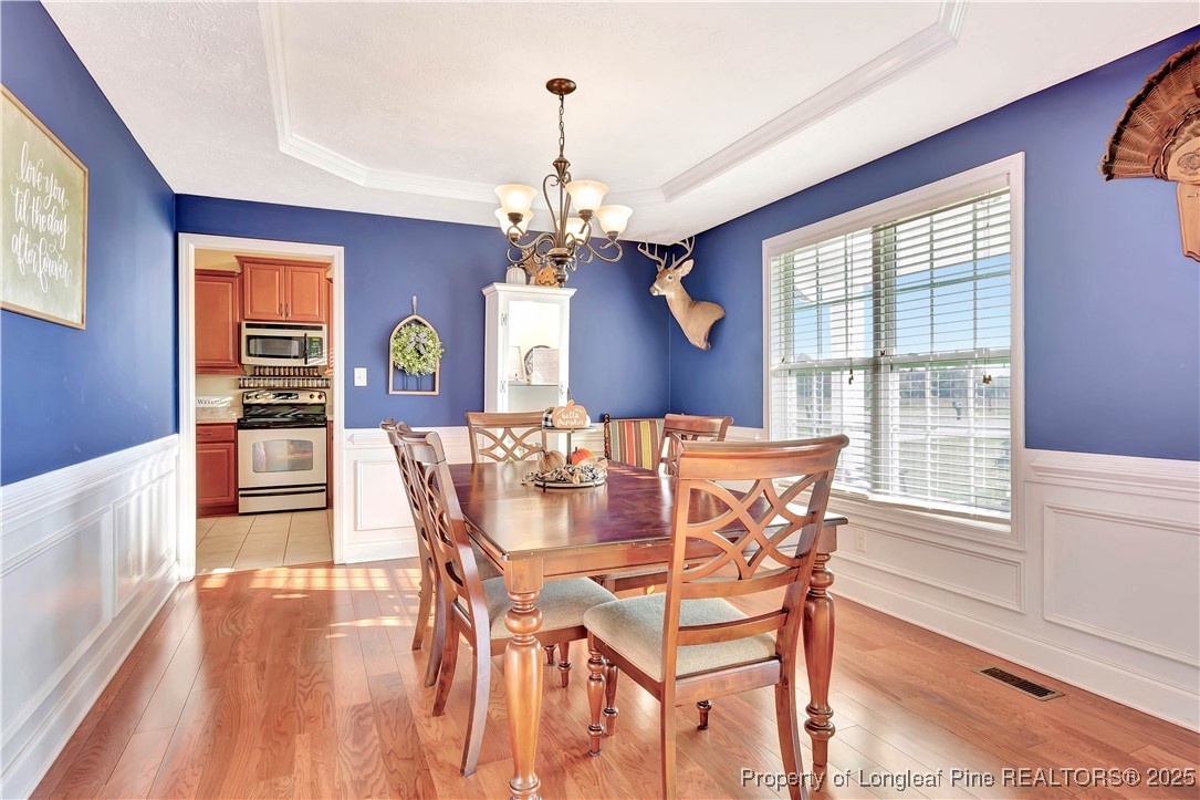 7453 7th Street Road Lumberton, NC 28358 - Photo 18 of 37 a dining room with wooden floor a chandelier a wooden table and chairs