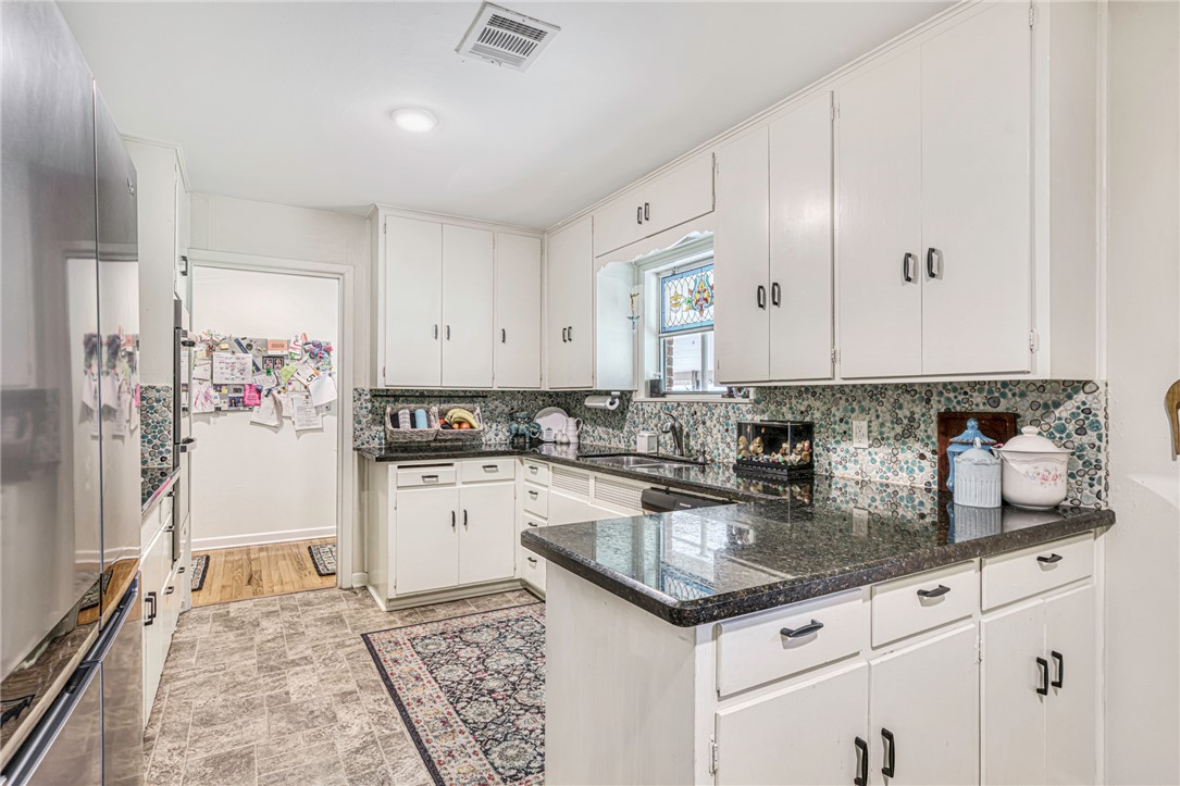 801 North Center Street Franklin, TX 77856 - Photo 13 of 32 Kitchen featuring a sink, backsplash, dark countertops, white cabinetry, and freestanding refrigerator