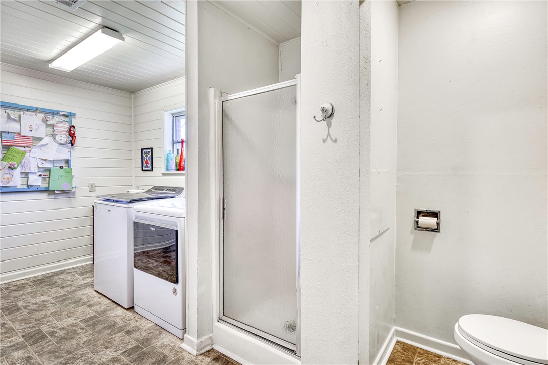 801 North Center Street Franklin, TX 77856 - Photo 17 of 32 Full bath featuring separate washer and dryer, a shower stall, toilet, wood walls, and baseboards