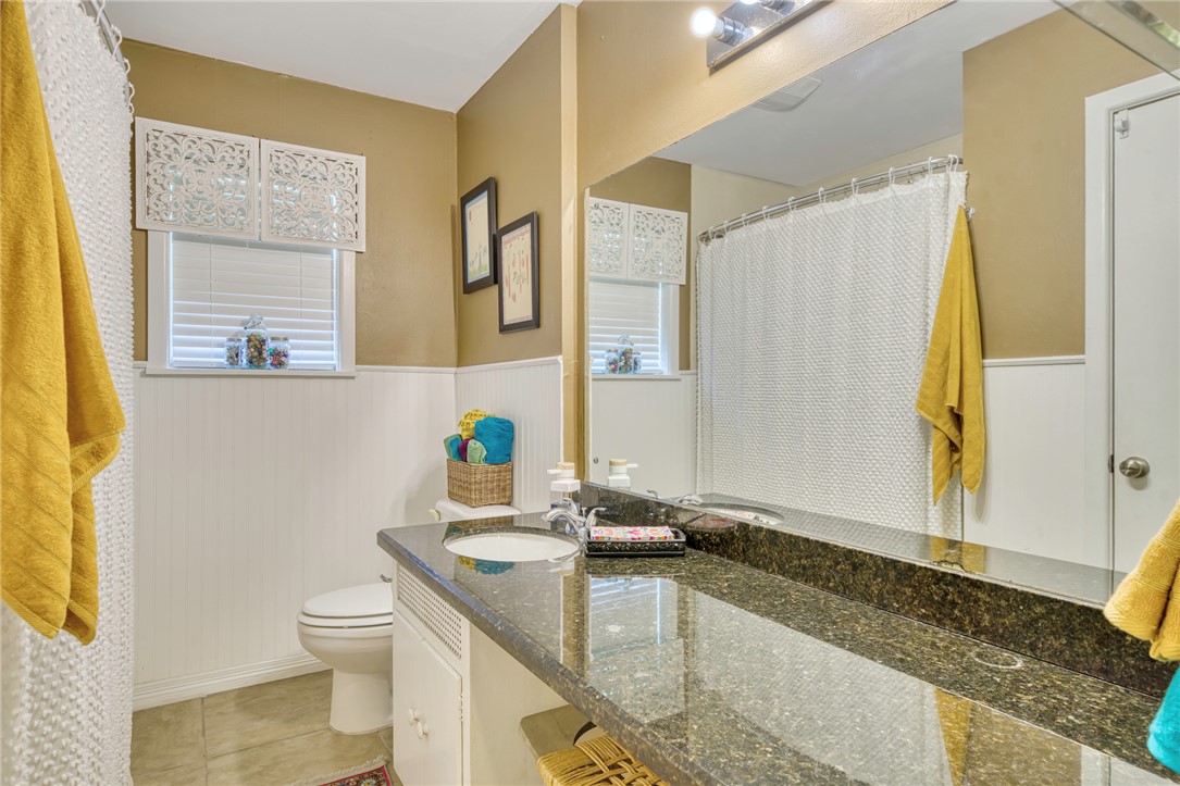 801 North Center Street Franklin, TX 77856 - Photo 25 of 32 Bathroom featuring toilet, vanity, a wainscoted wall, tile patterned floors, and healthy amount of natural light