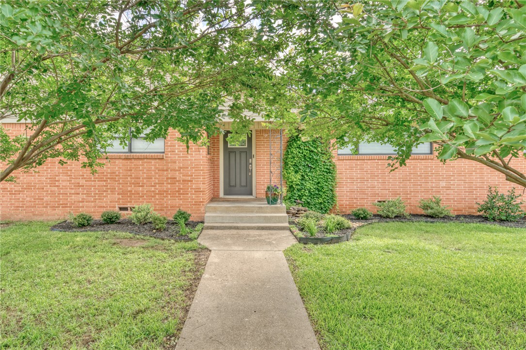 801 North Center Street Franklin, TX 77856 - Photo 6 of 32 View of exterior entry with brick siding, a lawn, and crawl space