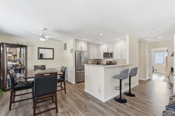 a living room with stainless steel appliances kitchen island granite countertop furniture and a dining table with wooden floor