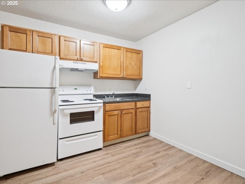 010 South Porter Street Portland, OR 97201 - Photo 4 of 11 a kitchen with granite countertop white cabinets and white appliances
