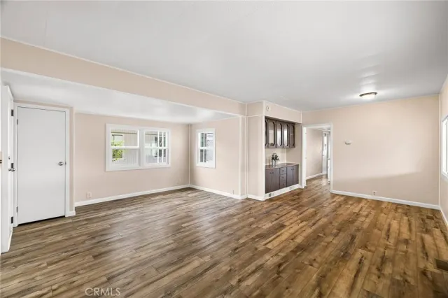 a view of an empty room with window and wooden floor