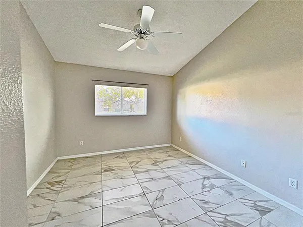 an empty room with windows and fan