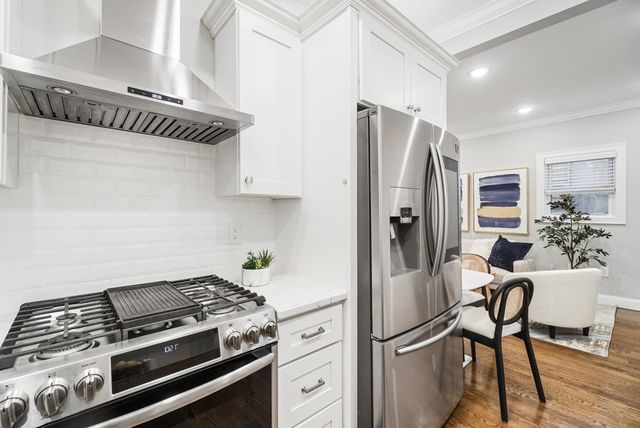 a kitchen with stainless steel appliances a refrigerator a stove and white cabinets