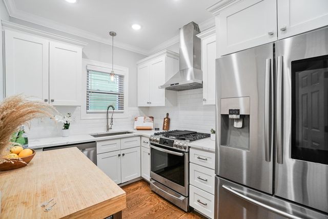 a kitchen with stainless steel appliances a sink a stove a refrigerator and cabinets