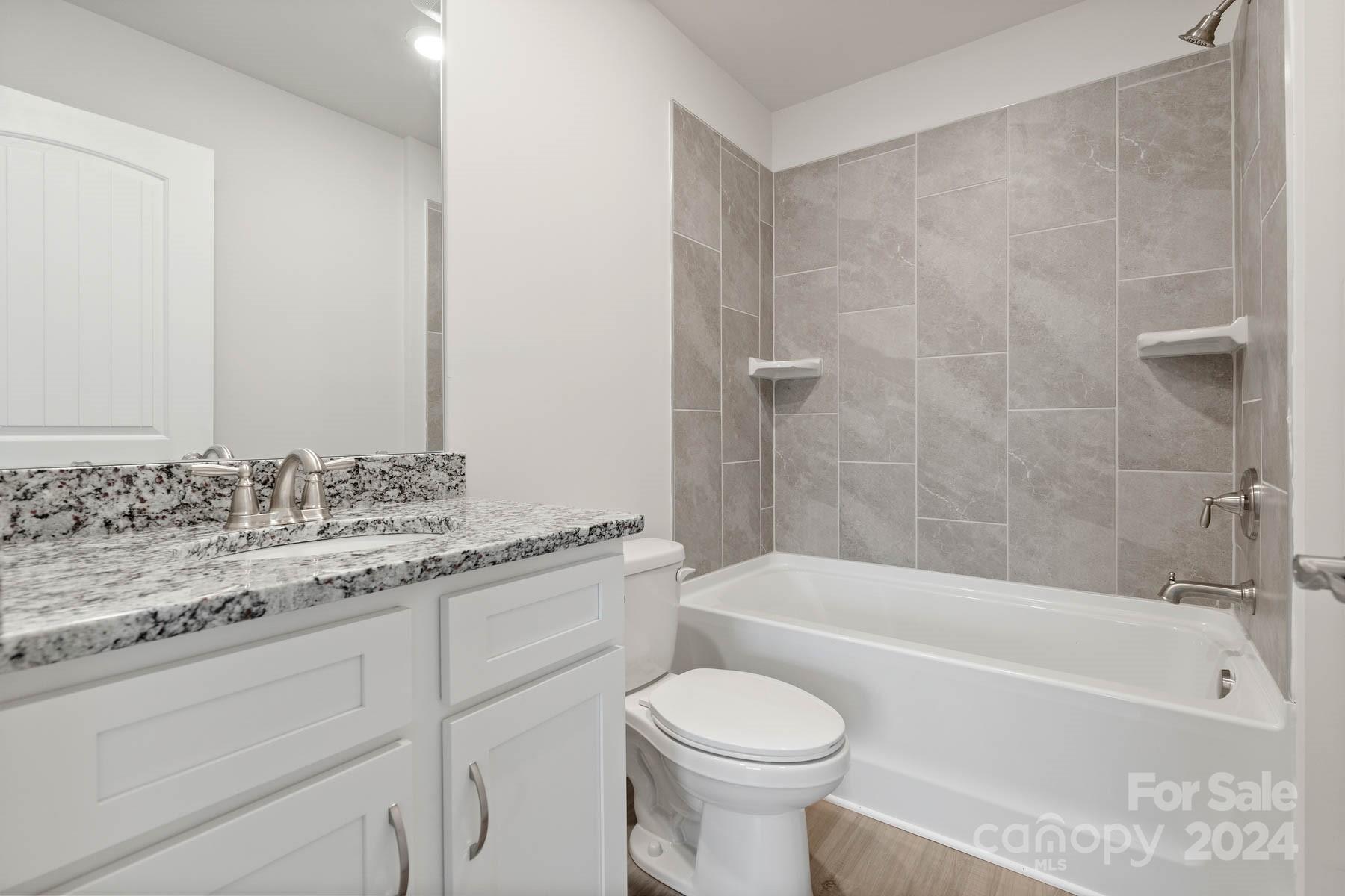 105 Brixham Loop Troutman, NC 28166 - Photo 13 of 13 a bathroom with a granite countertop sink a toilet and bathtub