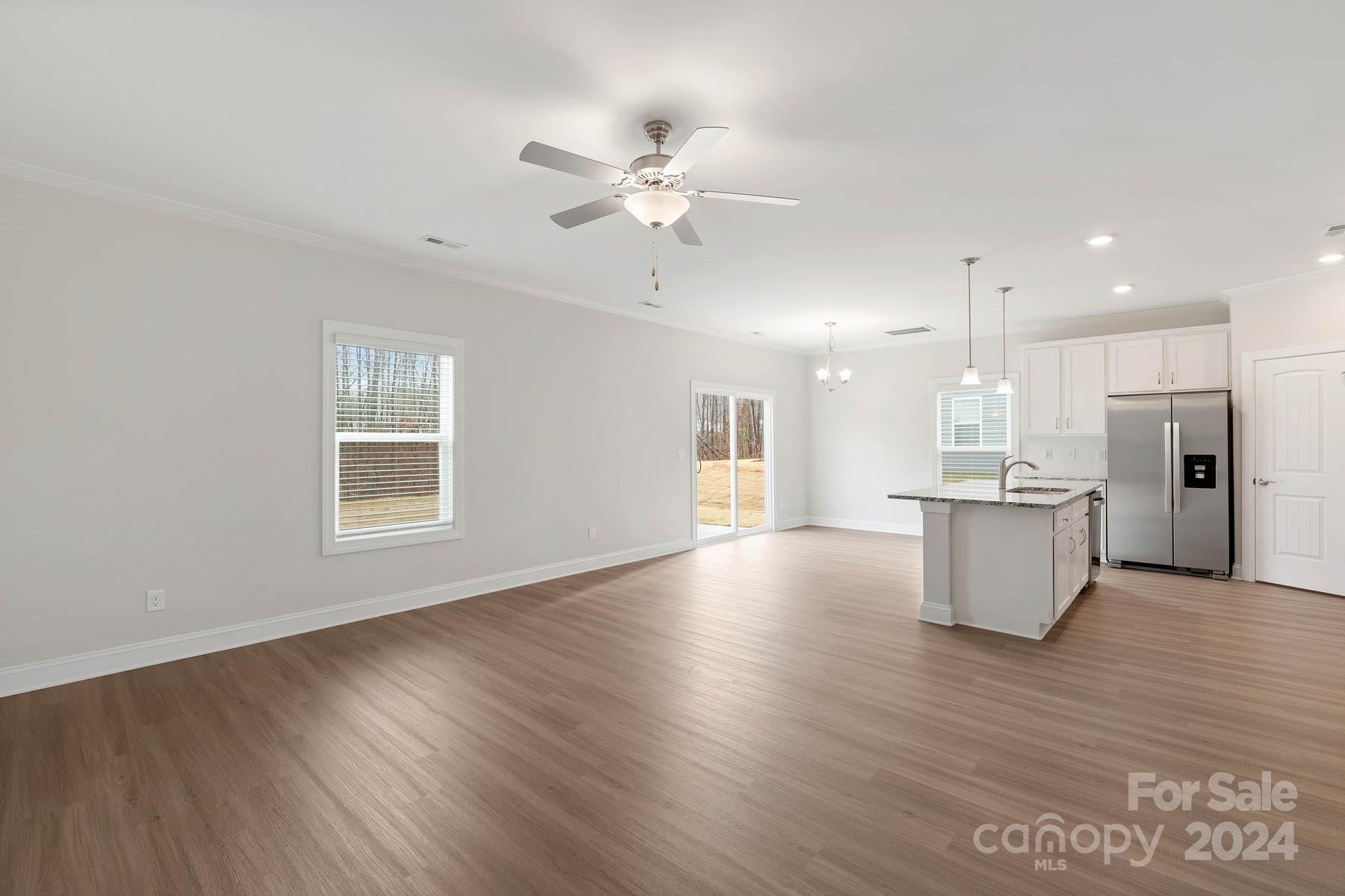 105 Brixham Loop Troutman, NC 28166 - Photo 3 of 13 a view of an empty room with wooden floor and a kitchen