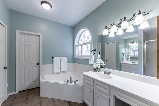 a spacious bathroom with a sink a large mirror and a bathtub