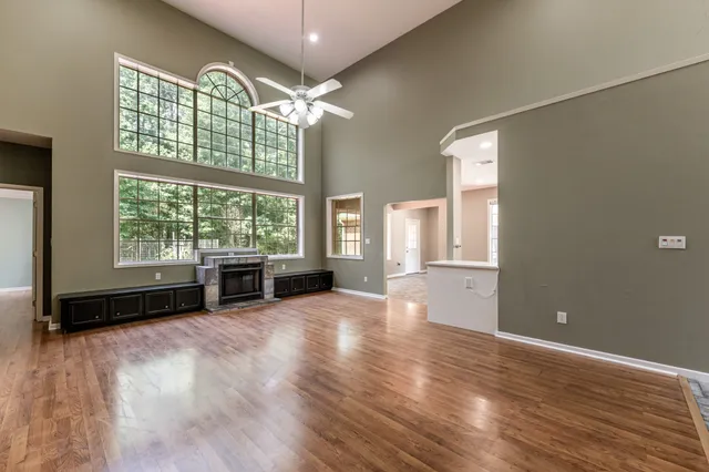 an empty room with wooden floor and windows