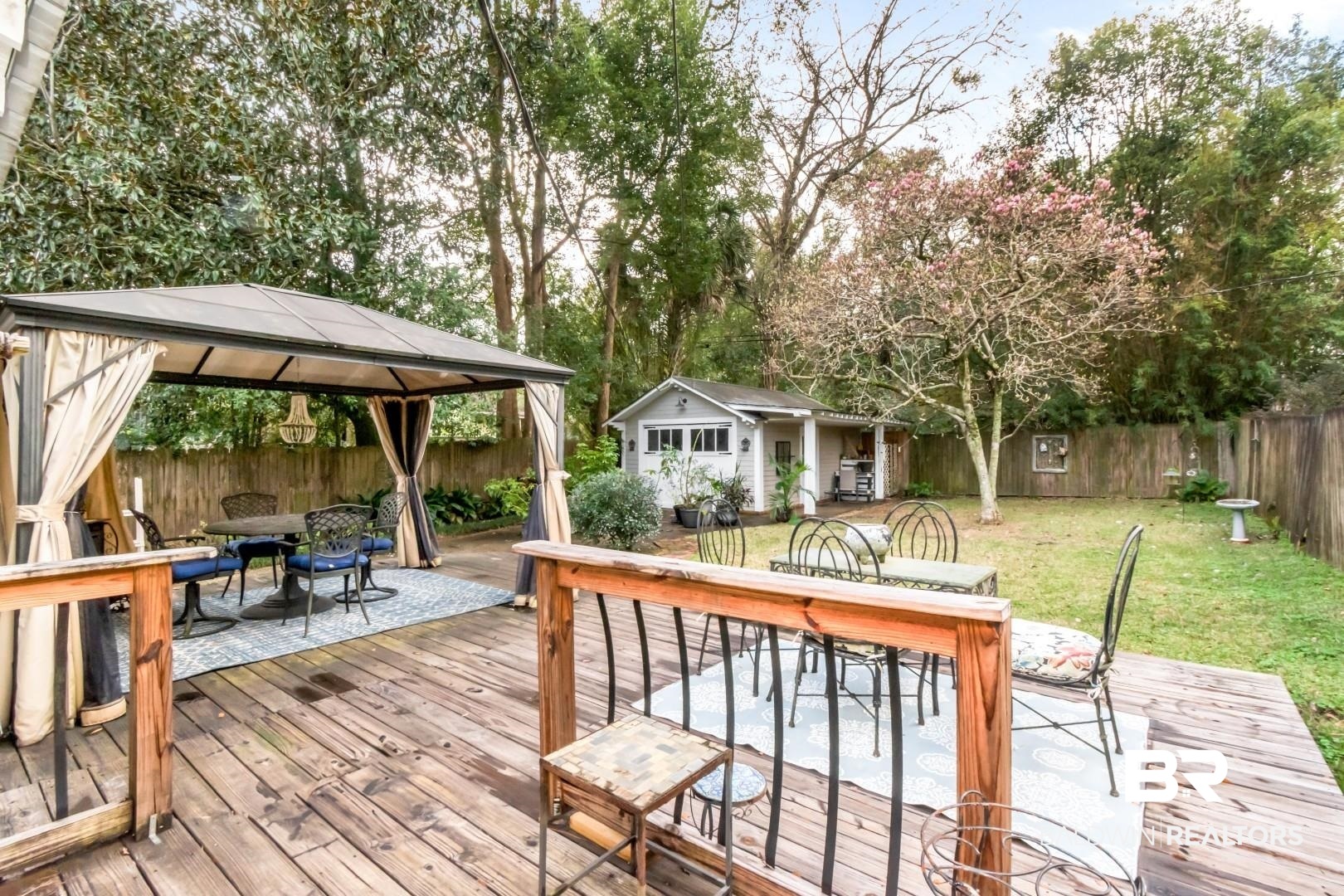 135 Silverwood Street Mobile, AL 36607 - Photo 20 of 32 Deck featuring outdoor dining space, a patio area, a fenced backyard, a gazebo, and an outdoor structure