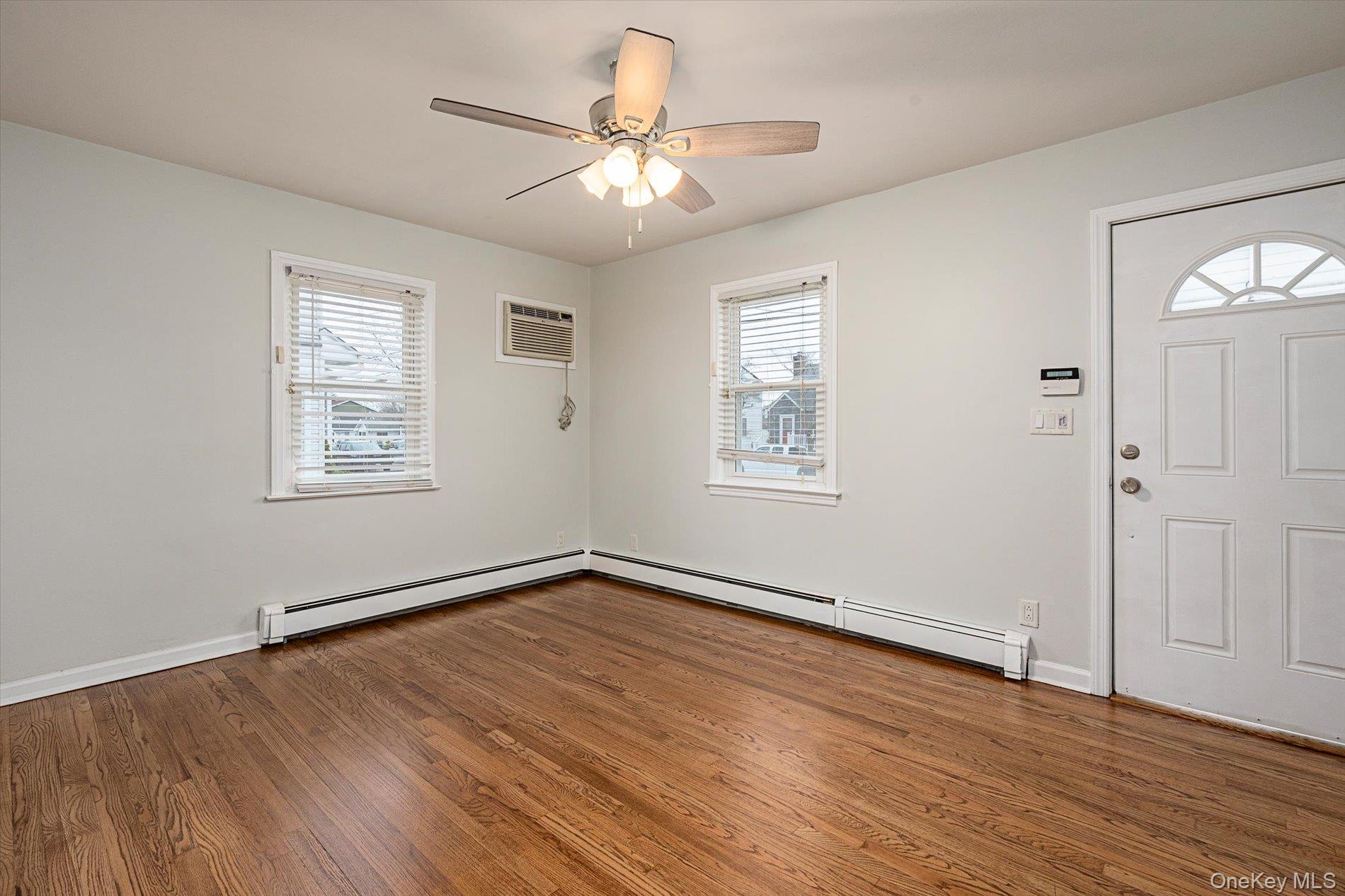20 Kenneth Avenue Bellmore, NY 11710 - Photo 6 of 24 an empty room with wooden floor chandelier fan and windows