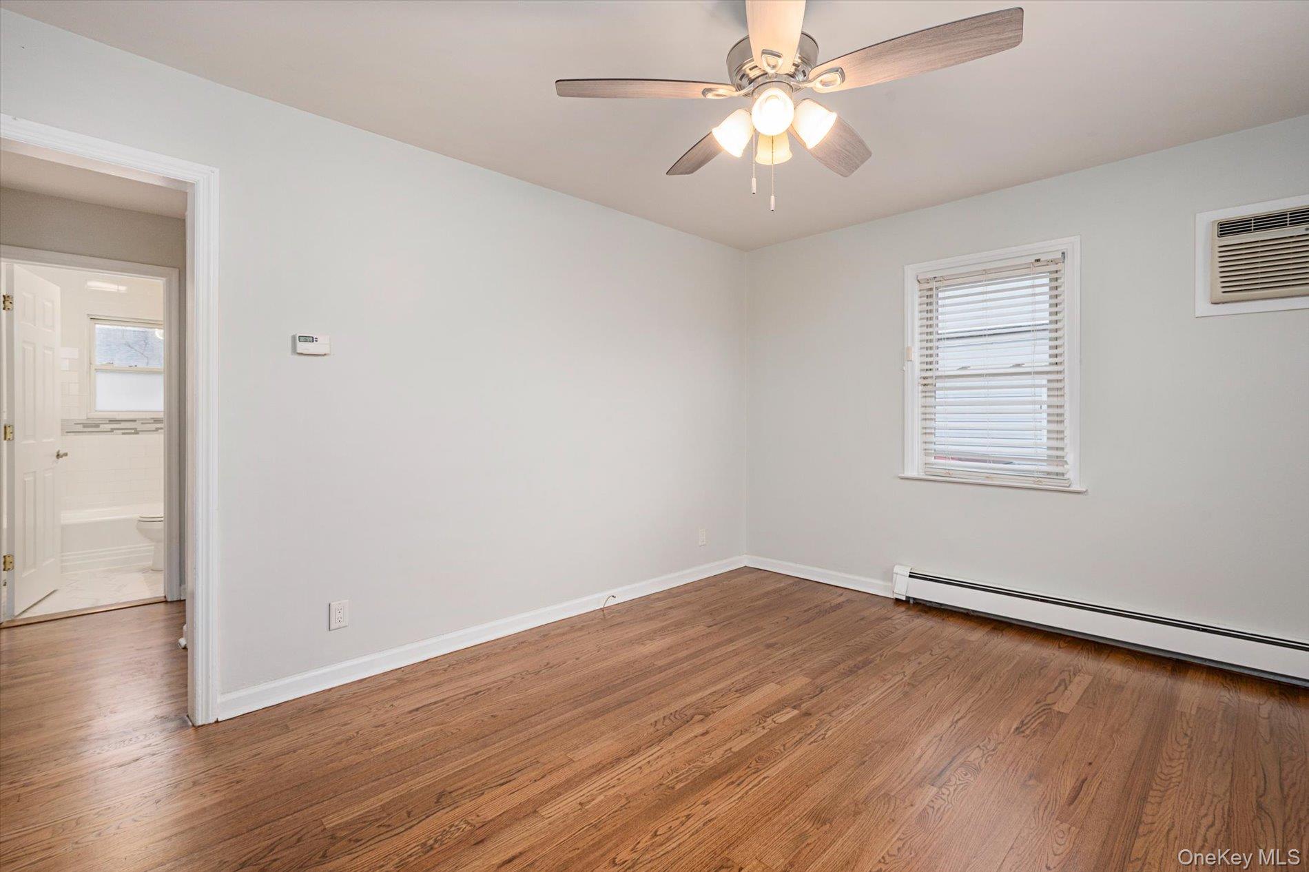 20 Kenneth Avenue Bellmore, NY 11710 - Photo 7 of 24 an empty room with wooden floor chandelier fan and windows