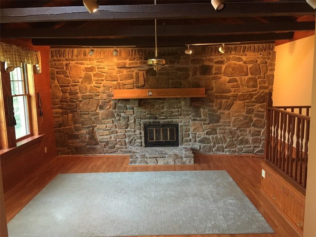 685 Pluto Road Ligonier, PA 15658 - Photo 4 of 25 Hardwood floor with stone fireplace wall and three windows to the left.