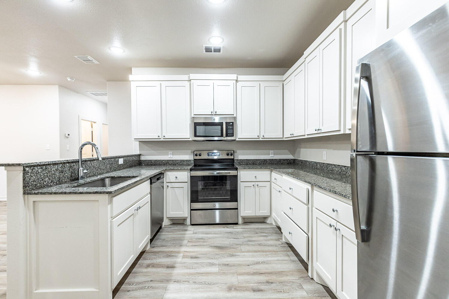 5502 Kemper Street Lubbock, TX 79416 - Photo 6 of 17 a kitchen with stainless steel appliances granite countertop a refrigerator a stove a sink and a microwave
