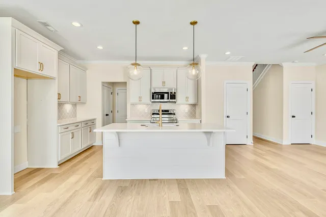 a view of kitchen with stainless steel appliances granite countertop a stove top oven a refrigerator a sink and white cabinets with wooden floor