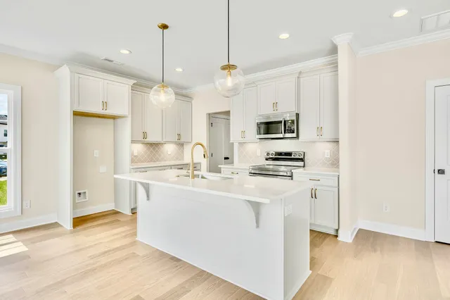 a kitchen with stainless steel appliances granite countertop a sink a stove a refrigerator and island with wooden floor