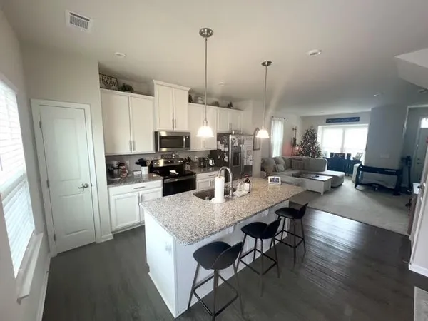a kitchen with stainless steel appliances granite countertop a stove refrigerator a dining table and chairs with wooden floor