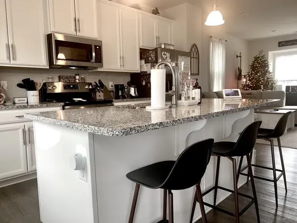 a kitchen with stainless steel appliances granite countertop a table chairs sink and cabinets