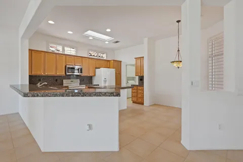 a large kitchen with stainless steel appliances granite countertop a stove a sink a refrigerator and a granite counter tops with a large window