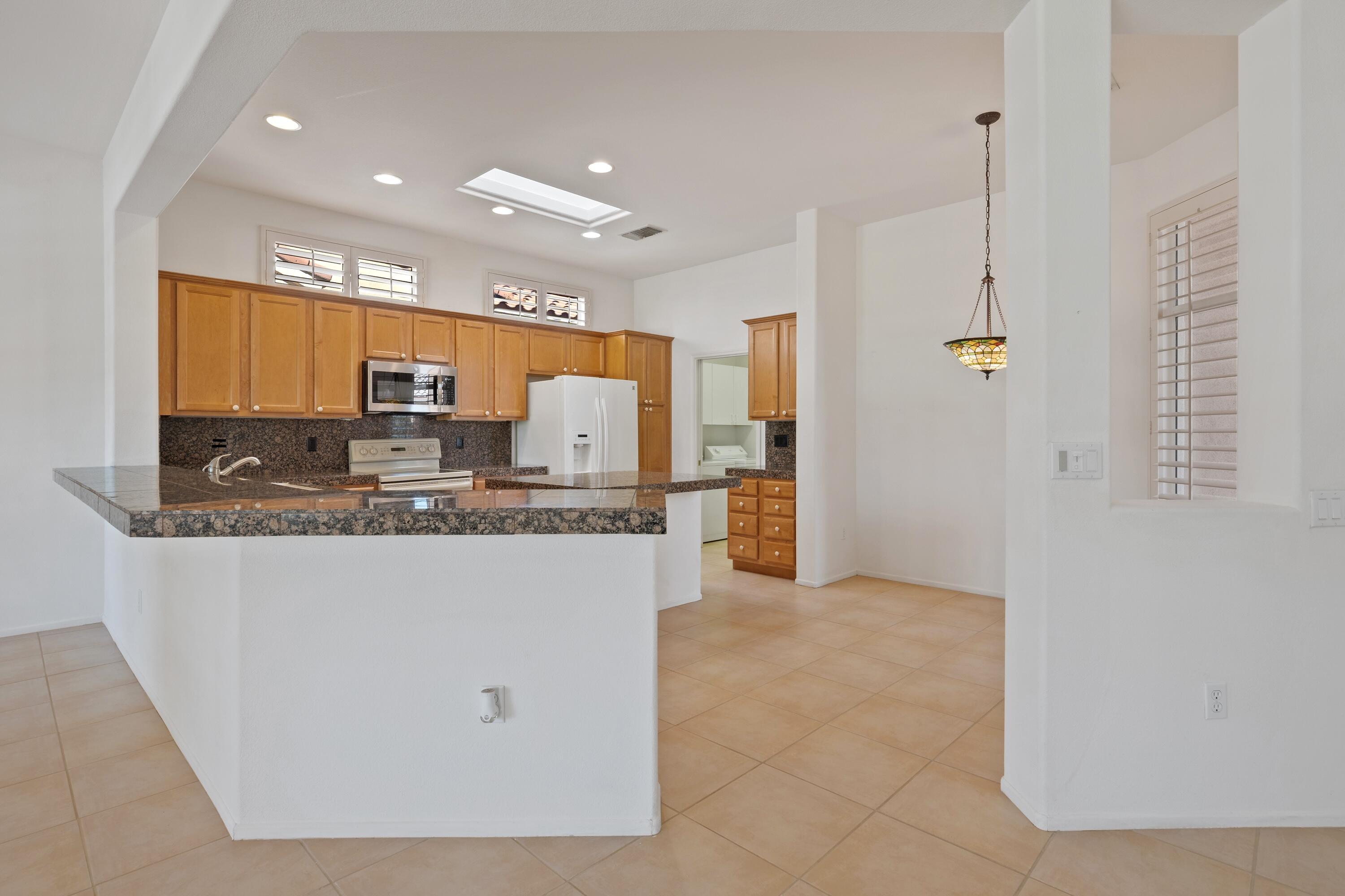 78513 Sunrise Mountain View Palm Desert, CA 92211 - Photo 18 of 45 a kitchen with stainless steel appliances granite countertop a stove a sink and a refrigerator