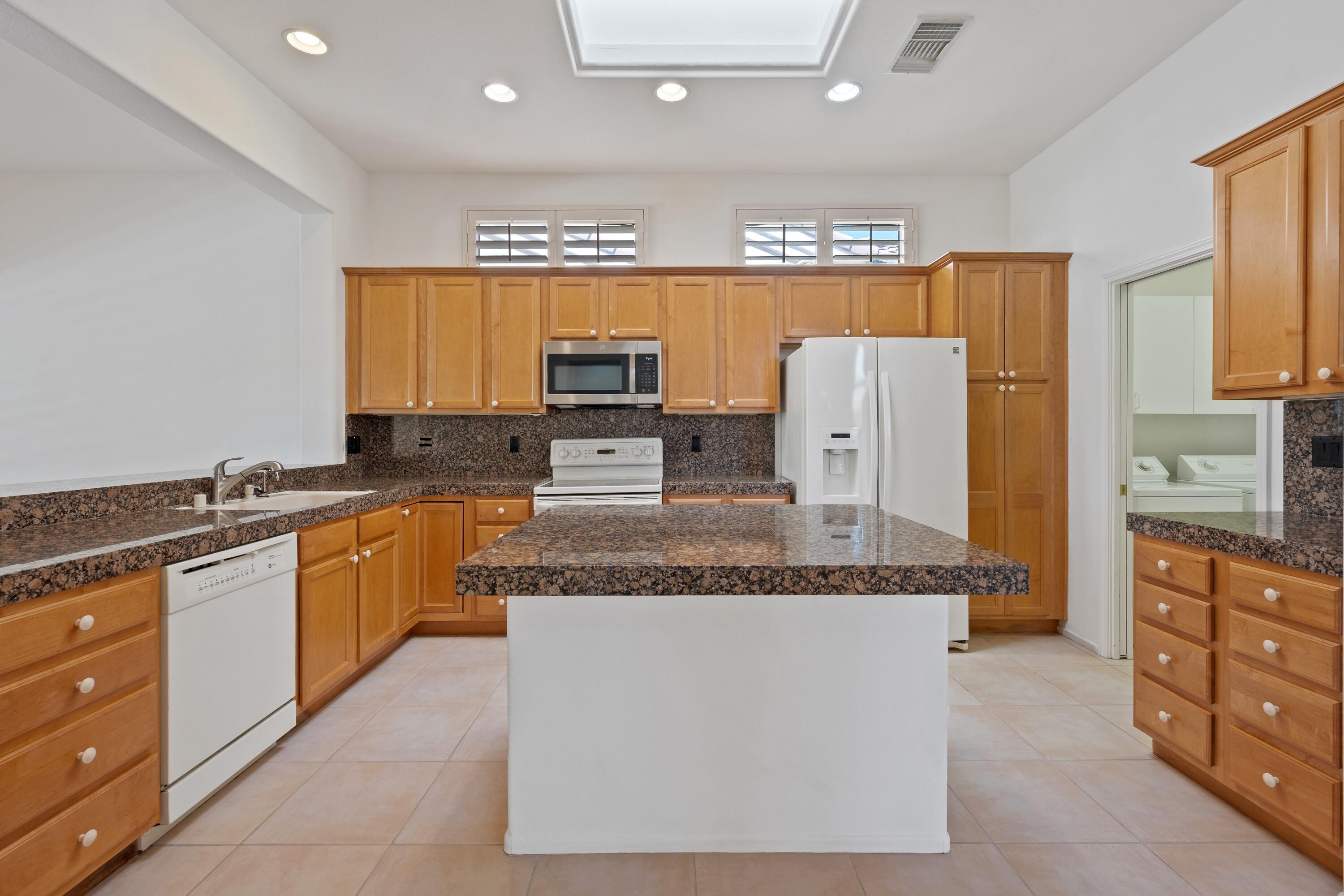 78513 Sunrise Mountain View Palm Desert, CA 92211 - Photo 19 of 45 a large kitchen with stainless steel appliances granite countertop a stove a sink a refrigerator and a granite counter tops with a large window