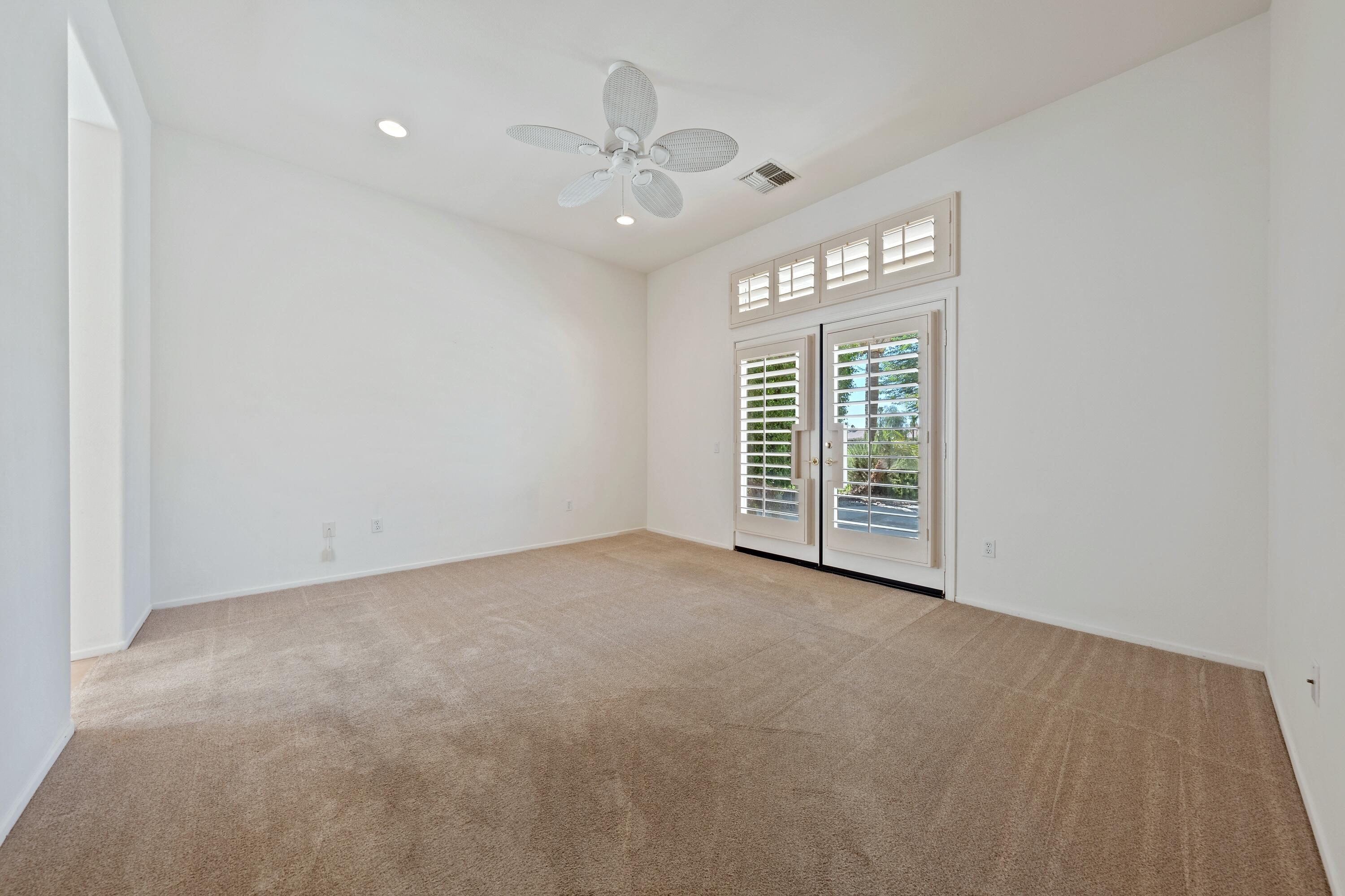 78513 Sunrise Mountain View Palm Desert, CA 92211 - Photo 26 of 45 an empty room with windows and chandelier fan