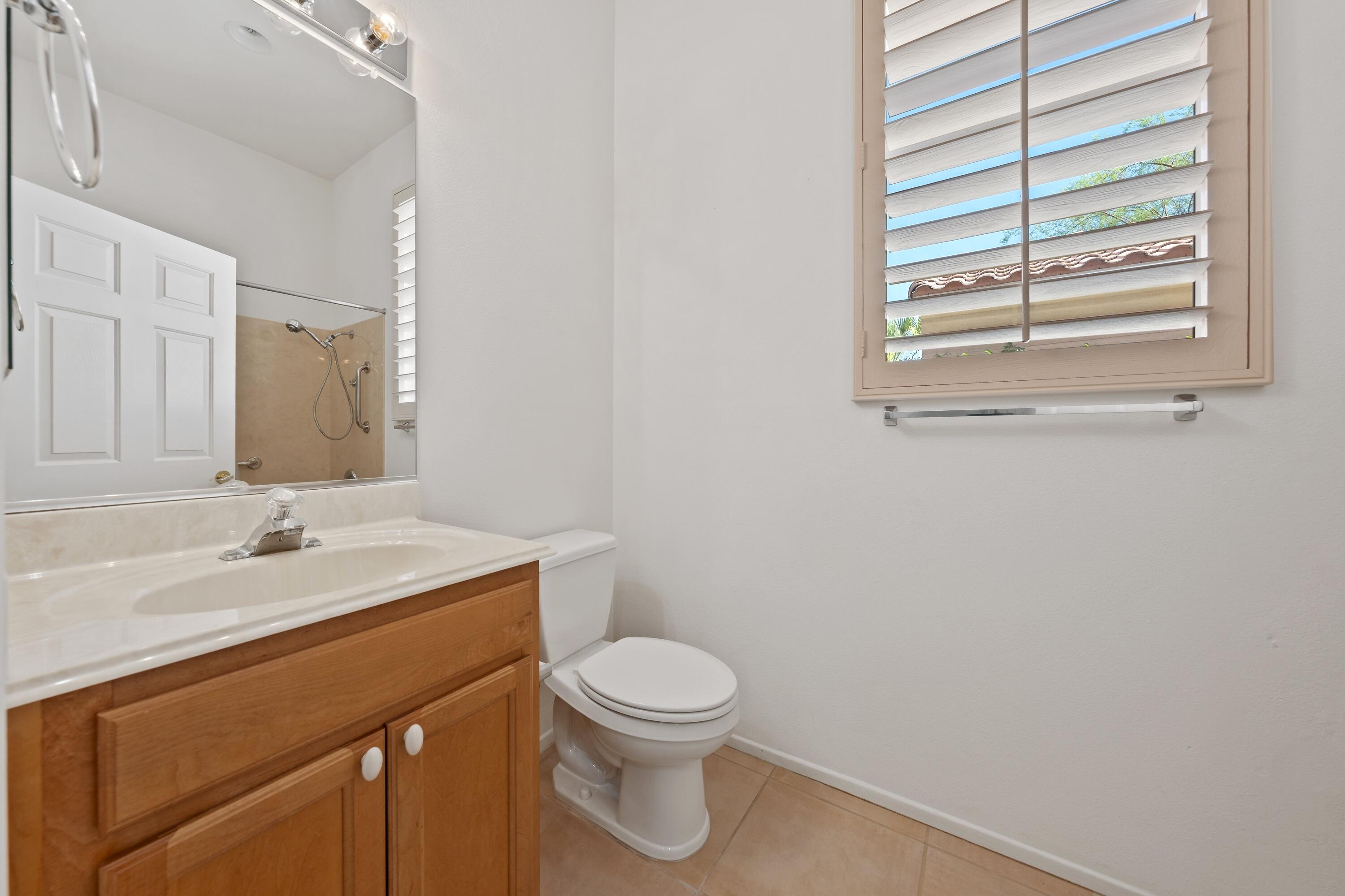 78513 Sunrise Mountain View Palm Desert, CA 92211 - Photo 34 of 45 a bathroom with a granite countertop toilet a sink a mirror and a window