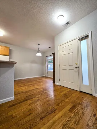 a view of an empty room with wooden floor and a ceiling fan