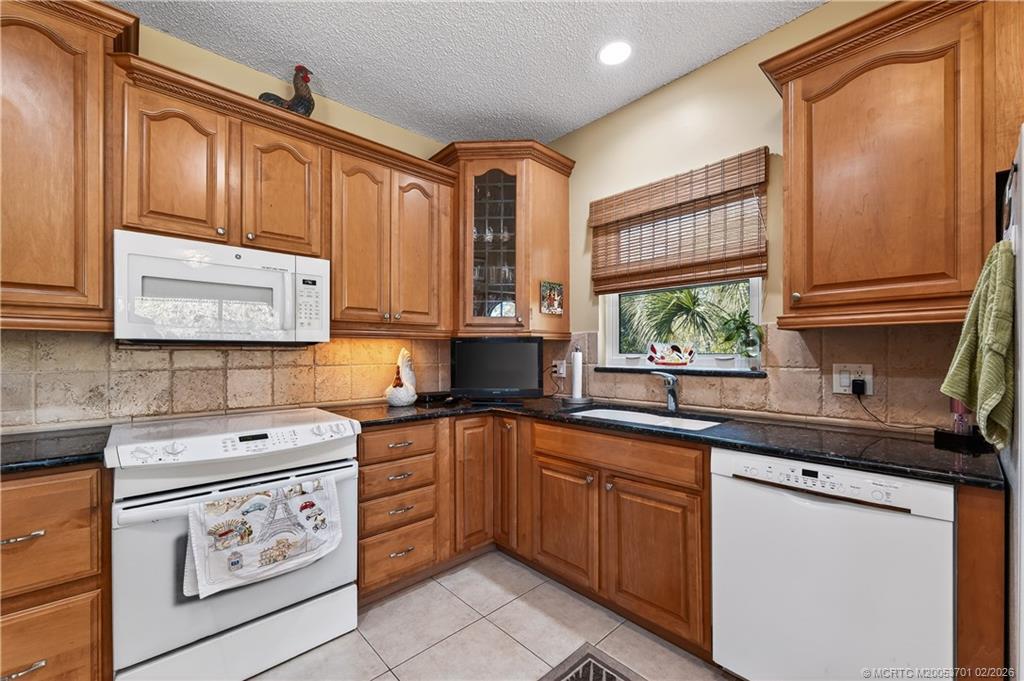 12415 Harbour Ridge Boulevard, Unit 48 Palm City, FL 34990 - Photo 13 of 34 a kitchen with stainless steel appliances granite countertop a sink stove cabinets and window