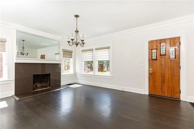 an empty room with wooden floor fireplace and windows